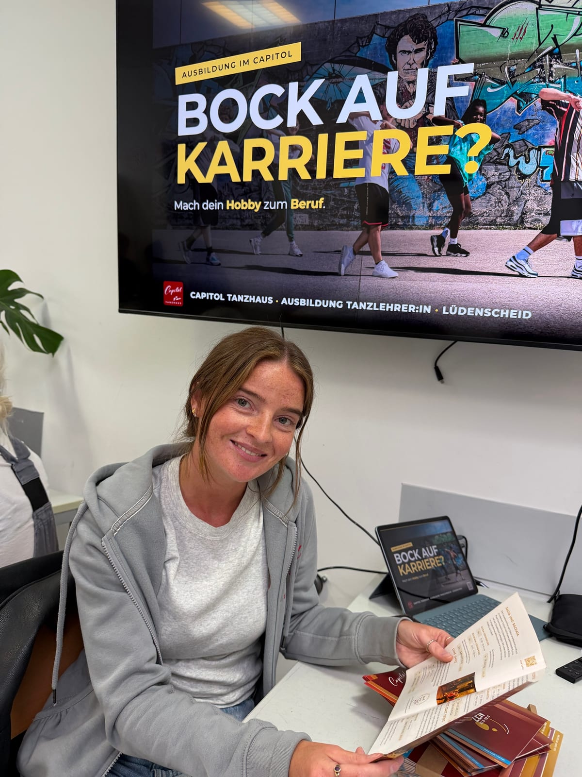 Unser Stand bei den ElternDays: Kollegin vom Capitol am Tisch mit Programmheften, darüber der Monitor mit „Bock auf Karriere?“